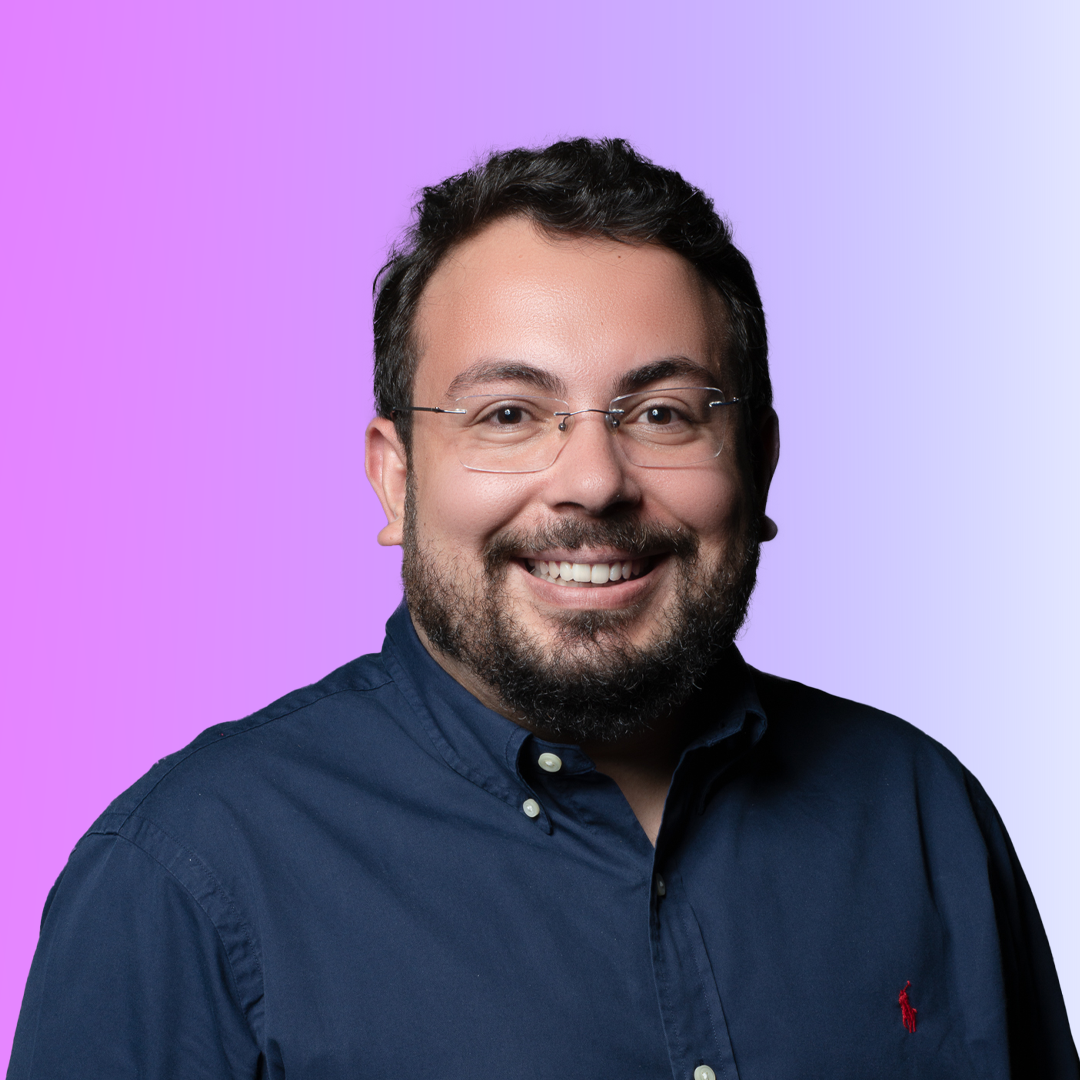 Uma foto de retrato de Pedro Teberga, um homem de meia-idade com cabelos grisalhos curtos e barba bem cuidada. Ele usa óculos de armação preta e uma camisa polo azul. O fundo é um gradiente azul suave, com o logotipo da Inteli no canto superior direito. Pedro olha diretamente para a câmera com uma expressão séria e profissional.