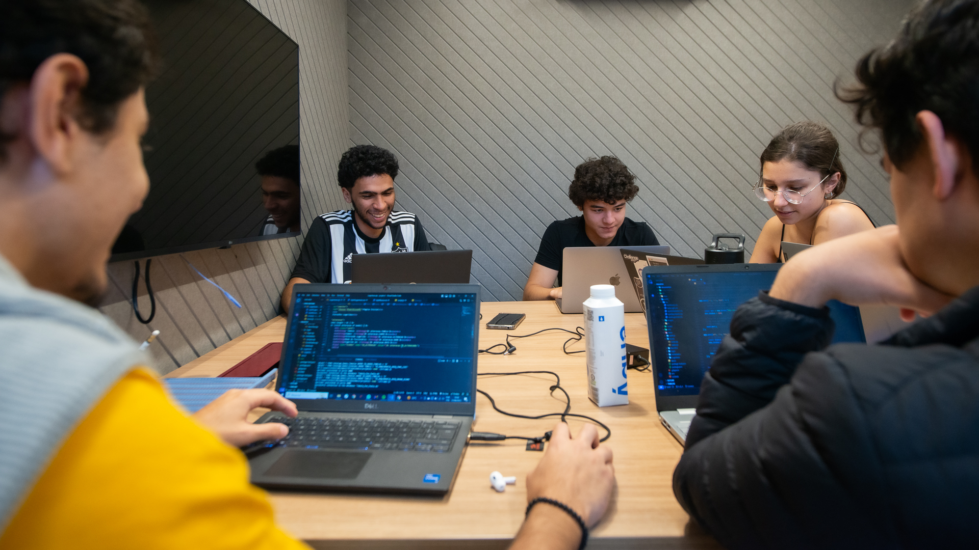 Alunos do Inteli programando em grupo com laptops durante projeto prático de tecnologia
